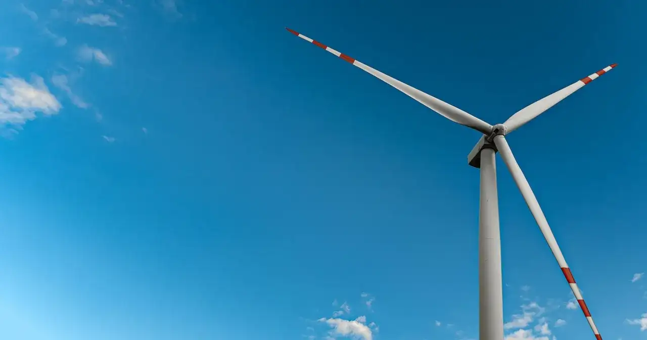 Wiatrak na tle błękitnego nieba, symbol czystej energii wiatru.