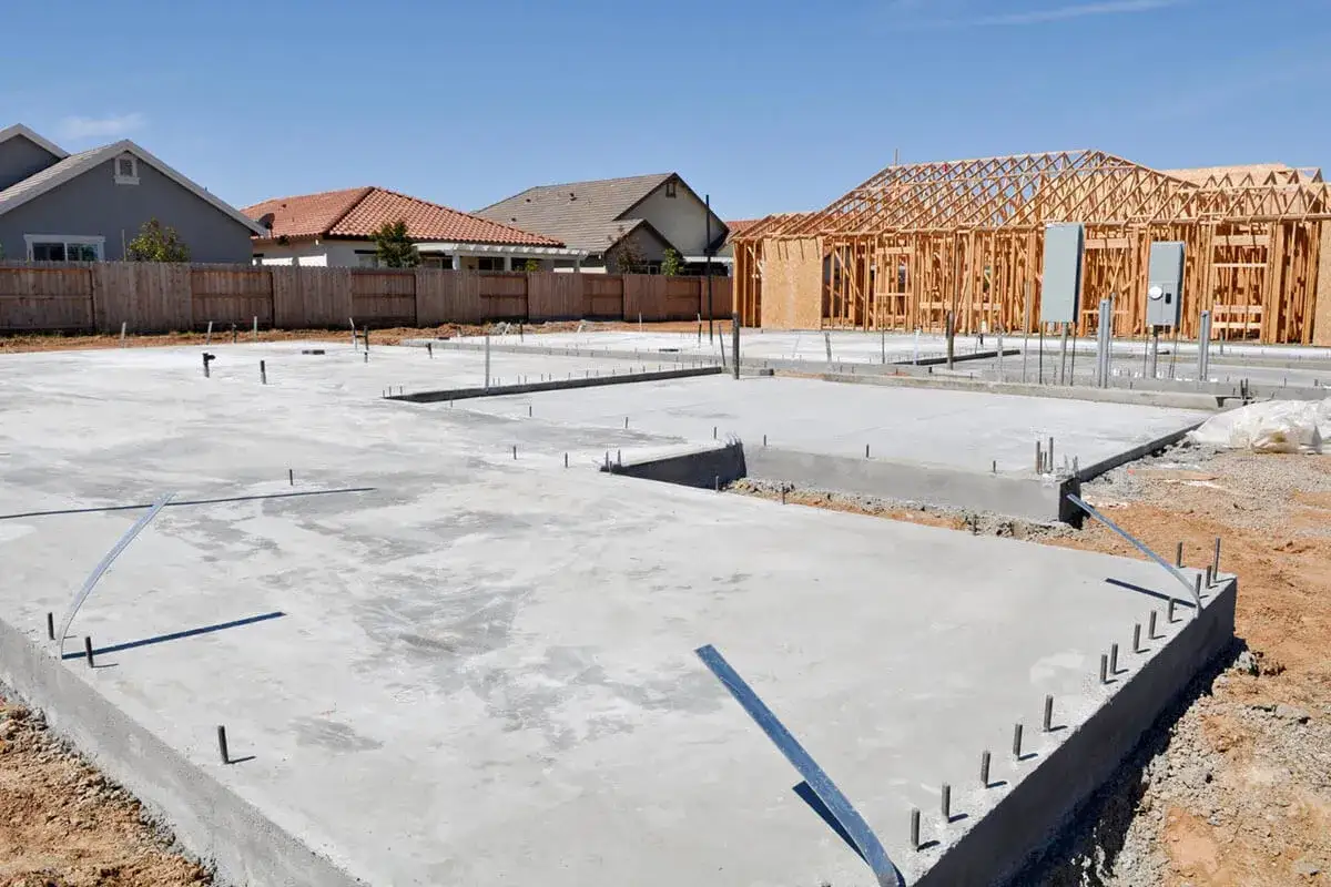 Fundamenty domów w budowie, widać chudy beton i szkielety drewniane.