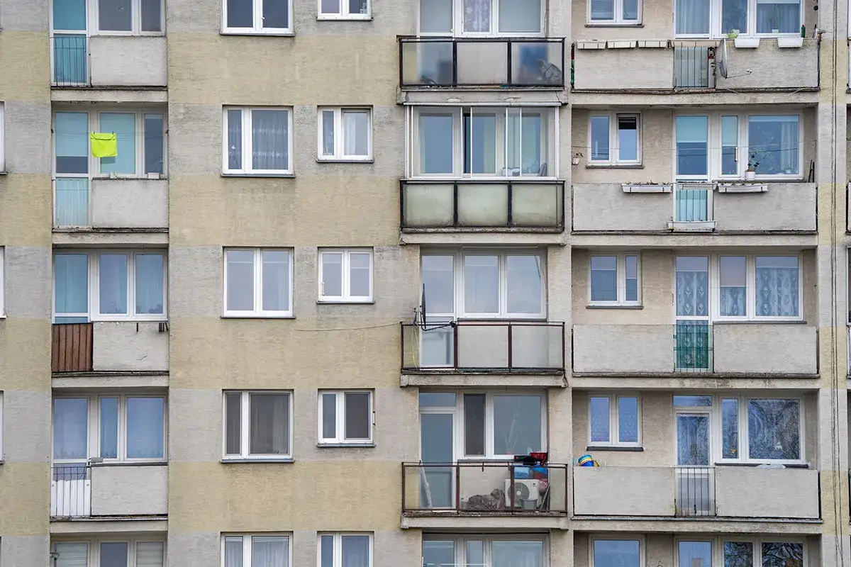 Fasada bloku z wieloma oknami i balkonami. Zastanawiasz się nad wymianą okien w bloku? Cena może być różna.
