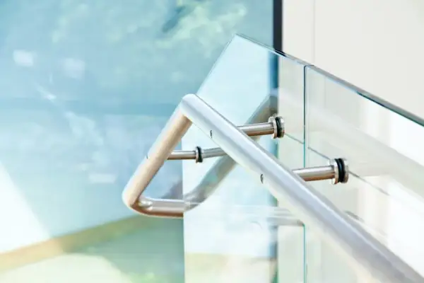 Nowoczesne mocowanie balustrady od czoła do szklanej tafli. Metalowy uchwyt pewnie trzyma się szkła, zapewniając bezpieczeństwo.