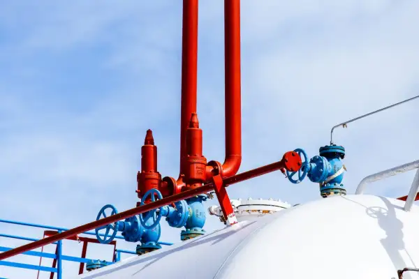 Zawory i rury na białym zbiorniku na gaz. Zastanawiasz się, na ile wystarcza zbiornik na gaz 2700?