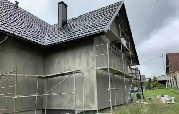 Dom w trakcie prac elewacyjnych, rusztowania wokół, szara ściana. Sprawdzamy elewacja cena za m2 robocizna.