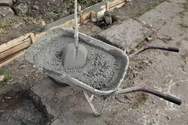 Taczka z betonem i łopatą czeka na wylanie fundamentów. Uziom fundamentowy w trakcie budowy.