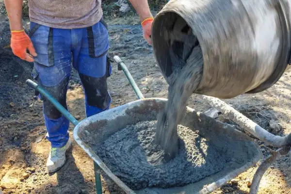 Robotnik wylewa beton B25 z betoniarki do taczki. Sprawdzamy beton B25 cena za m3.