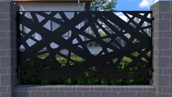 Czarna, ażurowa metalowa przegroda z geometrycznym wzorem, osadzona między kamiennymi słupkami.