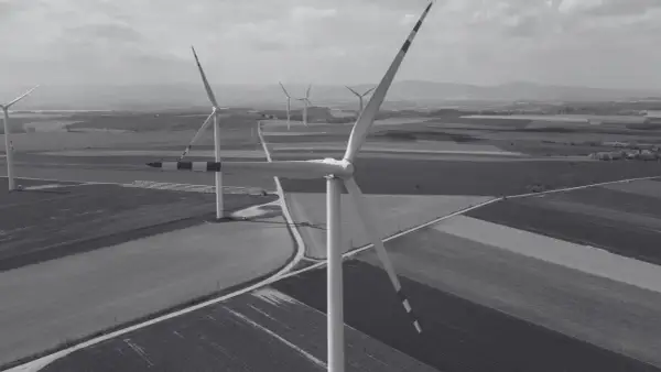 Wiatraki na tle pól i wzgórz. Nowa ustawa wiatrakowa sprzyja rozwojowi farm wiatrowych, tworząc zieloną energię.