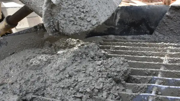 Świeży beton z kruszywem, idealny jako jaki beton pod obrzeża, wylewany na ruszt.